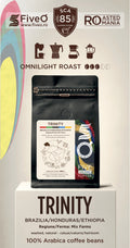 A coffee bag product display on a pedestal with branding for FiveO and Roasted in  Romania. The main subject is a black stand-up pouch labeled Trinity, with text indicating Omnilight Roast, Brazil/Honduras/Ethiopia origin, and 100% Arabica coffee beans.